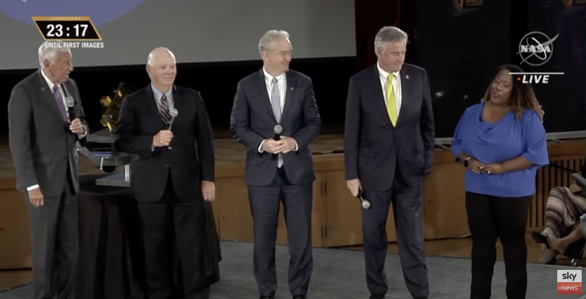 Four US congressmen in suits standing on stage at NASA Goddard